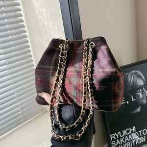 Vintage purple plaid wool bucket bag with gold chain strap in artistic indoor setting