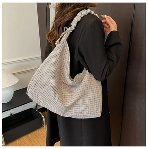 Detail view of a plaid hobo shoulder bag featuring ruffled wide straps on a model
