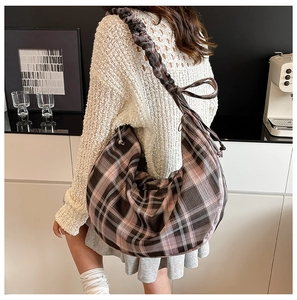 Detail of a large pink and brown plaid hobo bag with a stylish ruched scrunchie shoulder strap