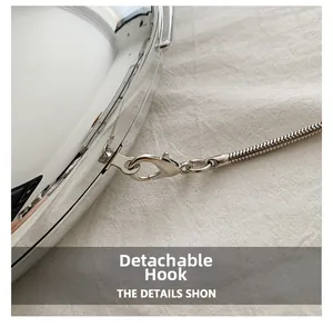 Macro detail of silver lobster clasp and sleek metal snake chain on linen background