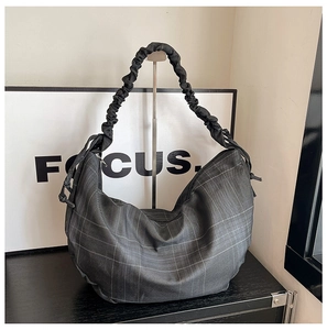 Detail of dark grey checkered shoulder bag featuring a pleated cloud-style strap design