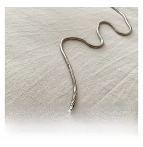 Close-up of a sleek silver snake chain strap on a soft textured fabric background