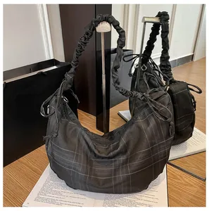 Detail of checkered hobo bag with drawstring sides and pleated shoulder strap detail