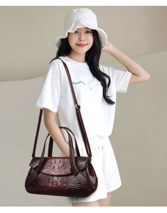 Dettaglio della borsa in pelle bordeaux con motivo a coccodrillo e dettagli metallici