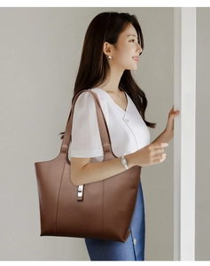 Detailed view of brown litchi grain leather tote bag featuring a silver metal twist lock