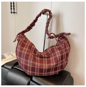 Detailed close-up of dark red checkered crescent bag with unique ruched shoulder strap