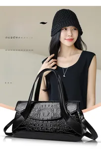 Detail of black crocodile embossed handbag with sturdy handles and glossy texture