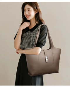 Detail of large brown leather tote bag with silver twist lock on an elegant model