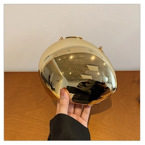 Detailed shot of a gold mirror acrylic evening clutch with unique oval design and chain strap