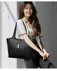 Close-up of black lychee-grain leather tote bag with silver twist lock on woman shoulder