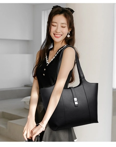 Detail of black lychee grain tote bag featuring a silver metal lock and vertical strap