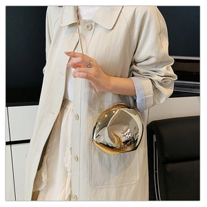 Detail of golden metallic teardrop evening clutch with sleek mirror finish and chain