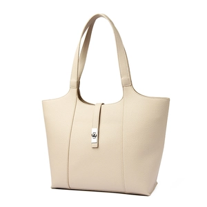 Detail of lychee pattern leather texture and silver metal twist lock on cream tote bag