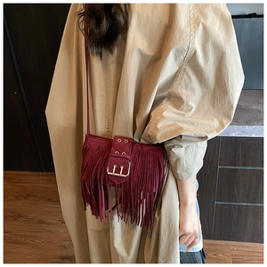 Détail du sac bandoulière bordeaux à franges avec boucle en métal et texture suède