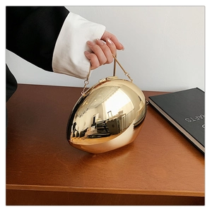 Detail view of a gold pebble-shaped evening clutch with polished mirror finish and chain
