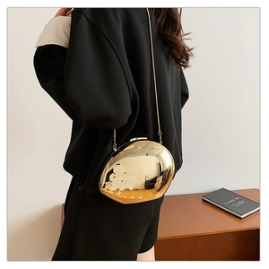 Close-up of golden irregular oval metal crossbody bag with mirror finish and chain strap