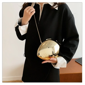 Detail of artistic gold pebble-shaped clutch bag with polished metallic mirror finish