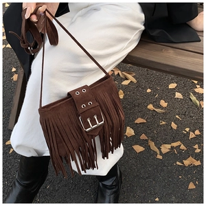 Détail d'un sac bandoulière en daim marron foncé avec de longues franges rétro et boucle