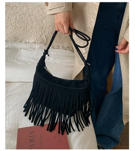 Detailed close-up of a black suede crescent bag with elegant long hanging fringes