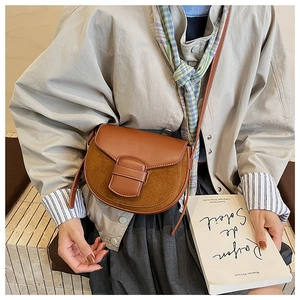 Detail of vintage brown saddle bag with suede texture and contrast stitching details