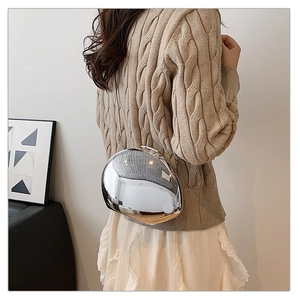 Silver mirror-finish pebble-shaped bag worn by a model with a metallic chain strap