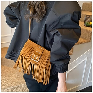 Détail d'un sac bandoulière marron à franges en daim avec une boucle métallique