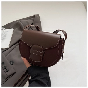 Detailed view of dark brown saddle bag featuring contrast white stitching and leather texture