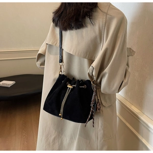 Detail of matte black bucket bag with gold chain strap and silk scarf accessory