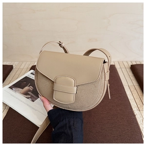 Detail of beige saddle bag with smooth flap and suede texture, showing the metal buckle