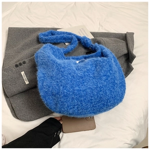 Detail of fluffy Klein blue faux fur shoulder bag with soft plush texture on white linen