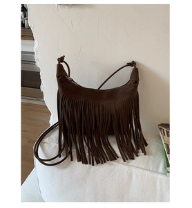 Detail of brown suede crossbody bag showing the long fringe texture and knotted strap