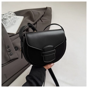 Close-up of black saddle bag with contrast white stitching and adjustable strap details