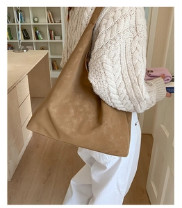 Detail of tan brown soft leather tote bag with embossed logo on cable knit sweater outfit