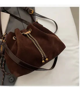Detail view of the drawstring closure and gold metal chain on a retro matte bucket bag