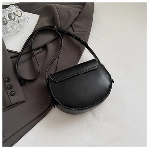 Close-up of black saddle bag with white contrast stitching and adjustable strap