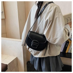 Close-up of black leather saddle bag featuring white contrast stitching and adjustable strap