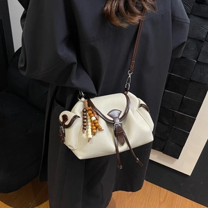 Chic beige canvas crossbody bag with brown leather trim and colorful wooden beads