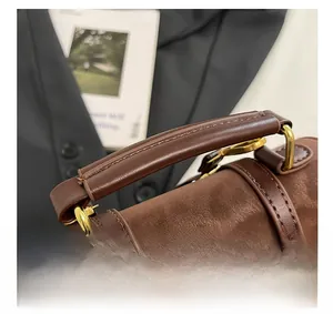 Gros plan détaillé de la poignée en cuir marron et boucles dorées sur sac à main