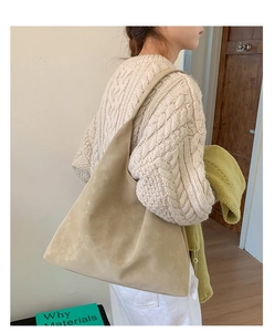 Detail view of large beige tote bag with soft matte texture worn over the shoulder