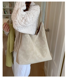 Detailed view of cream tote bag with cloud-dyed texture worn on shoulder indoors