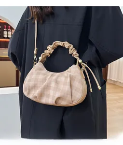Detail of checkered crescent bag with ruched handle and shoulder strap in warm beige