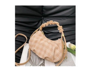 Detail of beige checkered cloud bag with pleated handle and golden zipper on black background
