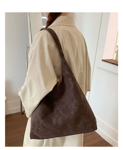 Detail view of large vintage brown tote bag worn with a chic beige trench coat