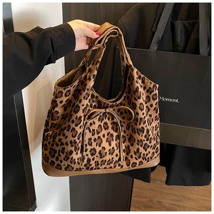 Detail of leopard print tote bag featuring a decorative bow and brown leather handles