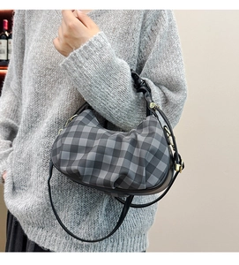 Detail of grey checkered pleated cloud bag with gold hardware and shoulder strap