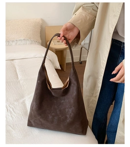 Macro detail of dark coffee frosted tote bag with minimalist matte leather texture and strap