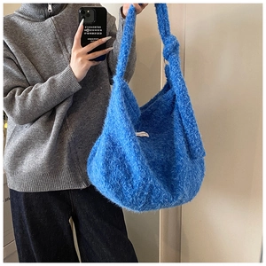 Detailed view of fluffy blue plush hobo bag with wide shoulder strap and label accent