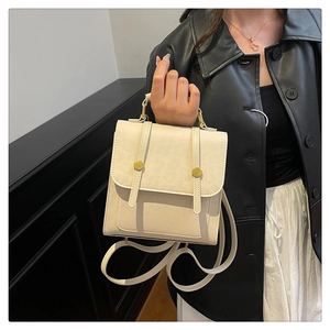 Vue latérale du sac à dos crème avec boucles dorées tenu par un mannequin