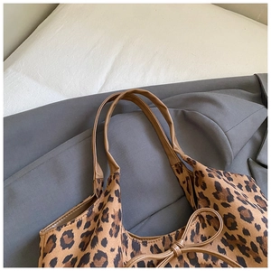 Detail of leopard print tote bag with brown leather handles and a bow embellishment