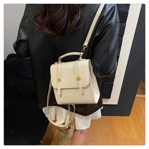 Détail d'un sac à dos vintage en cuir crème avec boucles dorées porté par un mannequin